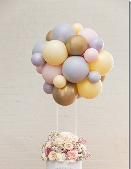 Cluster of 15 Pink Blue and gold balloons on the stick of a basket filled with 20 flowers