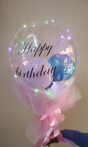 Happy Birthday Transparent Balloon tied with pink and blue balloons inside Led Lights and Pink wrapping Pink ribbons