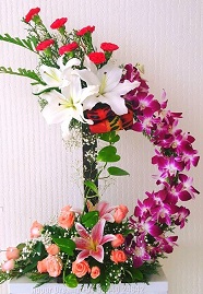 12 orange roses 1 Pink lily in the bottom basket with Curved 10 orchids reaching the top basket of 4 White lilies and 12 red carnations
