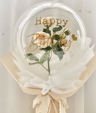 A bouquet of single clear balloon with happy birthday printed wrapped in white and jute