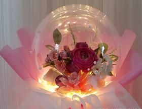 2 Red and pink rose and petals with leaves inside clear balloon with warm lights