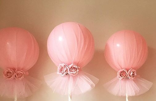 Three clear balloons covered with pink net and flowers