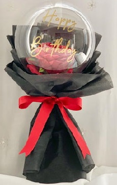 Print message on balloon with happy birthday and red roses inside wrapping in black with red ribbon product is in bouquet shape